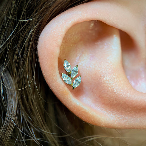 Close-up of an ear wearing a crystal leaf-shaped piercing.