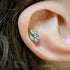 Close-up of an ear wearing a crystal leaf-shaped piercing.